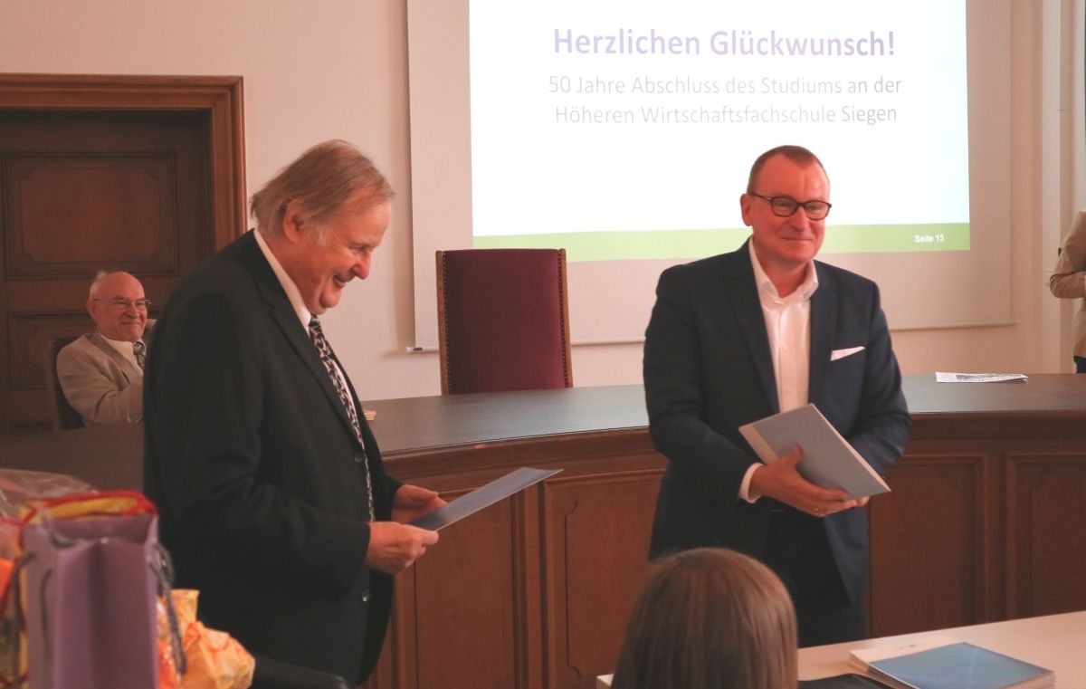 PD Dr. Michael Gail, Geschäftsführer der Fakultät Wirtschaftswissenschaften, Wirtschaftsinformatik und Wirtschaftsrecht der Universität Siegen übergibt den Alumni ihre Jubiläumsurkunden