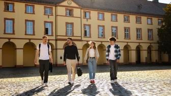 Vier Studierende laufen über den Campus Unteres Schloss.