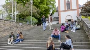 Mehrere Studieren sitzen auf den Treppenstufen vor der Nikolaikirche