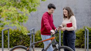 Zwei studierende stehen vor einem Fahrrad.