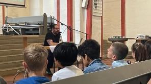 Autor Benjamin Tienti las zur Eröffnung in der Nikolaikirche vor Siegener Schüler*innen.