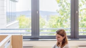 Studentin sitzt an Schreibtisch vor geöffnetem Laptop