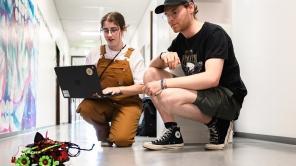 Studierende mit Laptop programmieren ein Auto