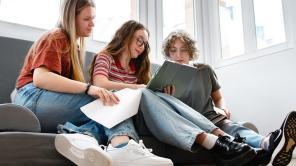 Studierende sitzen um einen Laptop