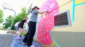 Zwei Frauen besprühen mit Graffiti-Spraydosen eine Wand.