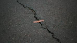 Riss im Asphalt, über das ein Pflaster geklebt ist
