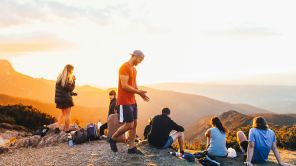 Junge Menschen ruhen sich nach einer Wanderung auf einem Hügel aus.