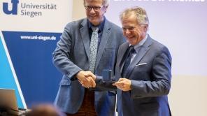 Prof. Dr. Ansgar Büschges überreicht die Daidalos-Münze an Prof. Dr. Thomas Mannel