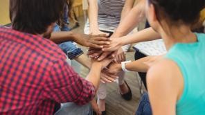 Menschen führen ihre Hände in der Mitte zusammen als Zeichen für Inklusion.