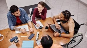 Diverse group of young people studying together in college library.