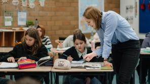 Klassenzimmer: Studentische Lehrerin hilft einer Schülerin