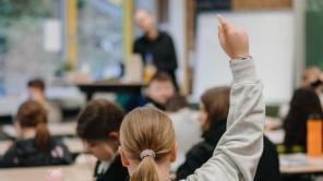 Klassenzimmer von hinten: Ein Kind meldet sich