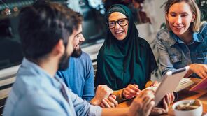 Internationale Studierende sitzen zusammen und erklären/lernen