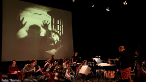 Ein Orchester vor einer Leinwand