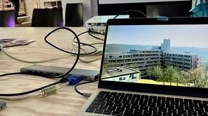 Eine Powerpoint-Präsentation, im Vordergrund auf dem Laptop, im Hintergrund von einem Beamer projiziert.