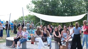 Gruppe von Studierenden, die auf Bänke auf der LEO-Wiese sitzen