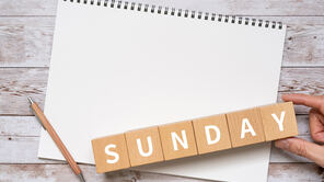 Foto mit einem leeren Kalenderblatt, einem Bleistift und dem Wort Sunday aus Holzklötzchenin Holz