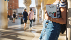 Female tourist in Venice holding a book on Italy in her arm.