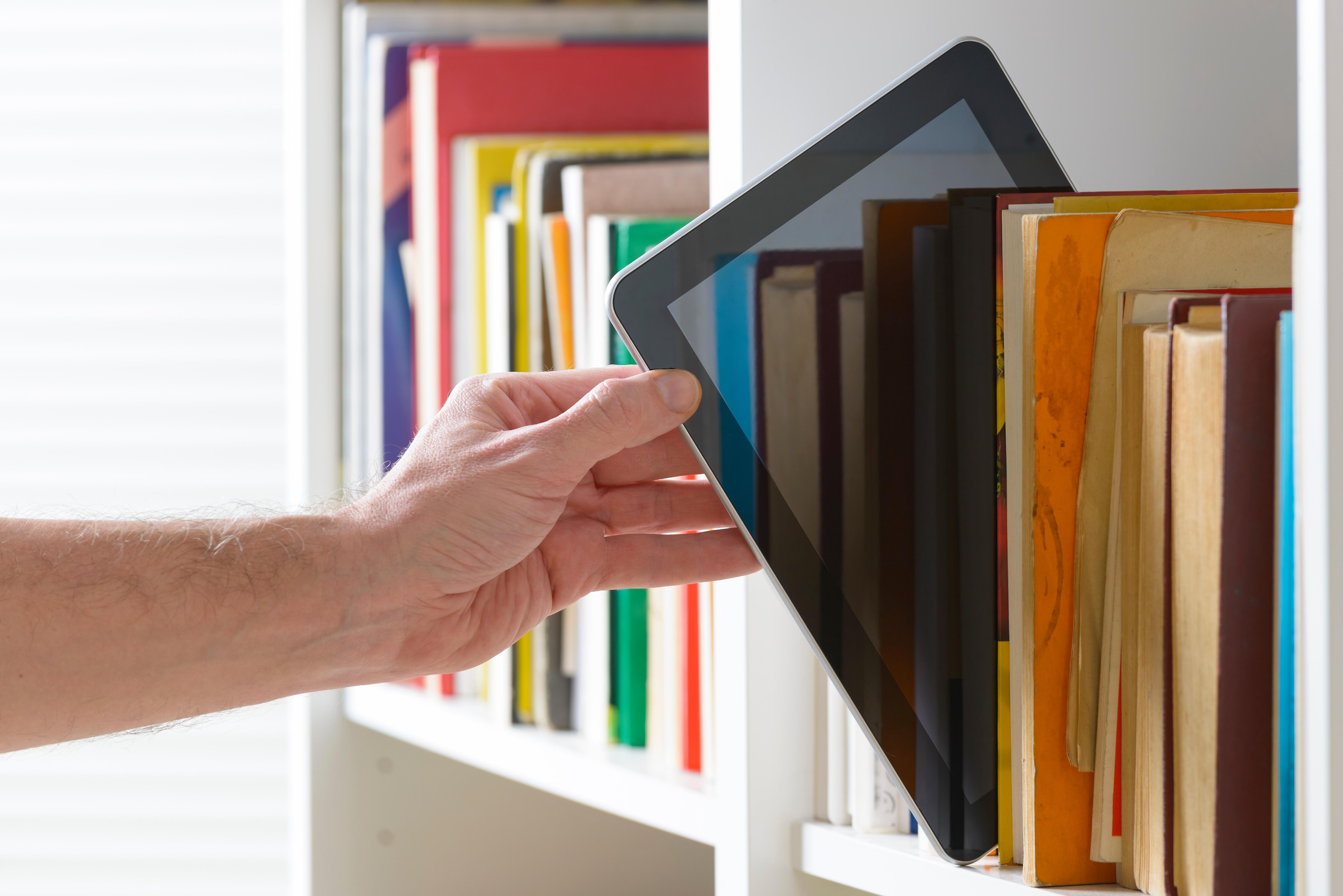 Ein Tablet wird aus einem Bücherregal genommen