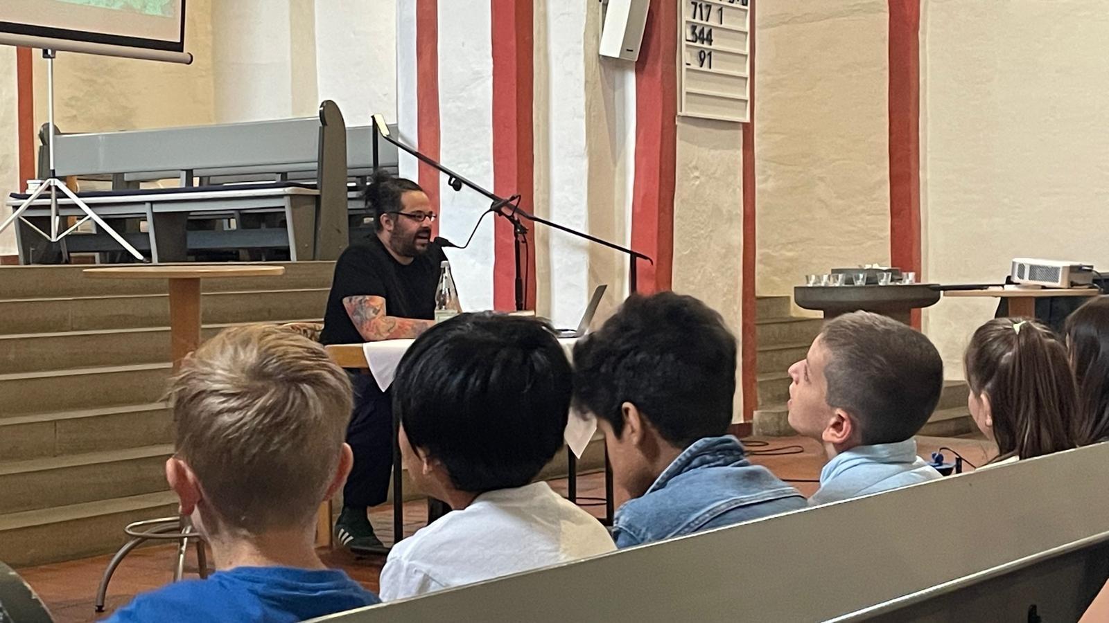 Autor Benjamin Tienti las zur Eröffnung in der Nikolaikirche vor Siegener Schüler*innen.