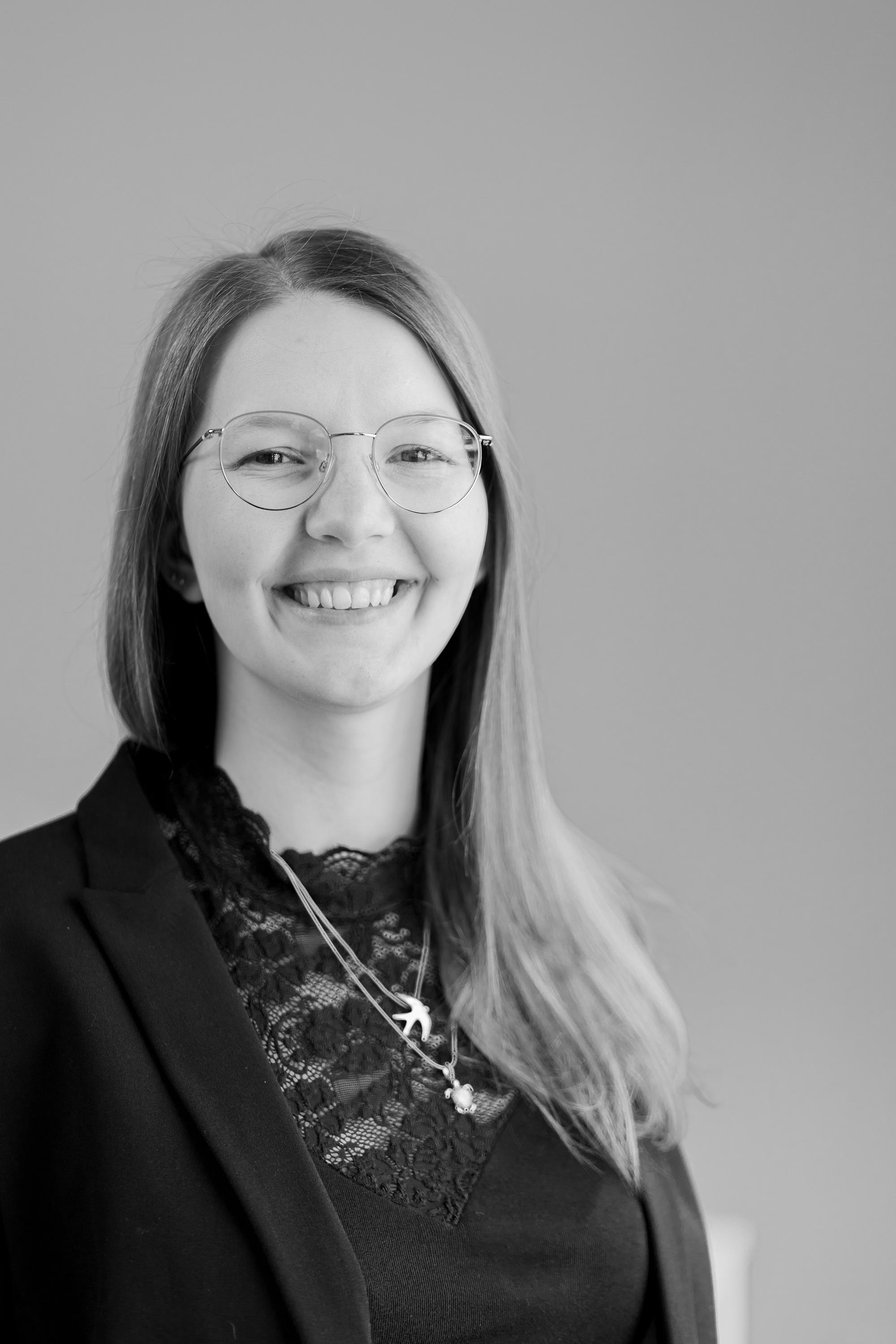 Eine Frau mit Brille und einem breiten Lächeln, die in die Kamera schaut.