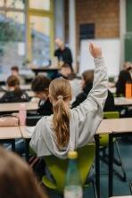 Klassenzimmer von hinten: Ein Kind meldet sich
