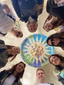 Studierende und Lehrende blicken herab mit einer Mosaikdecke im Hintergrund