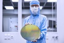Paul Kienitz hält im Reinraum einen Wafer in die Kamera.