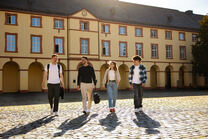 Studierende laufen über den Schlossplatz am Unteren Schloss