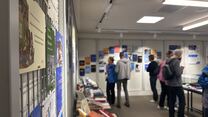 Ausstellung "25 Jahre universi". Im Vordergrund ist ein Cover scharf zu sehen, im Hintergrund Menschen, die die Ausstellung besuchen.