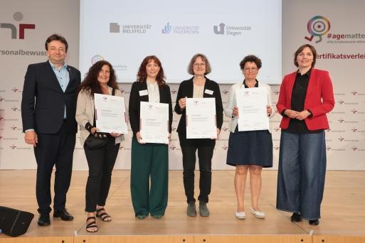 Gruppenbild der Preisverleihung &quot;familiengerechte hochschule&quot;: Gleichstellungsbeauftragte Elisabeth Heinrich (Uni Siegen) steht in der Mitte zwischen weiteren Vertreter*innen von zertifizierten Hochschulen.