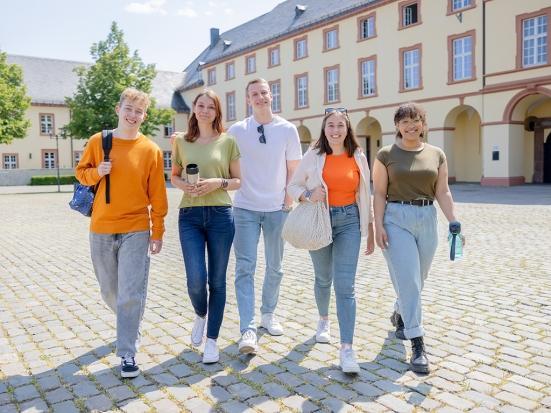Fünf Studierende laufen über den Campus Unteres Schloss