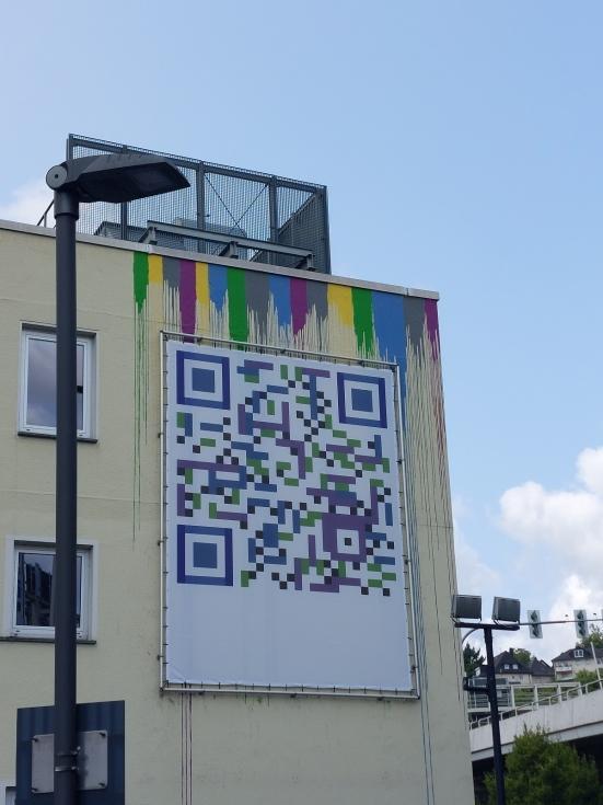 An der Fassade des Siegener SVB-Gebäudes hängt ein großer Banner mit einem QR-Code.