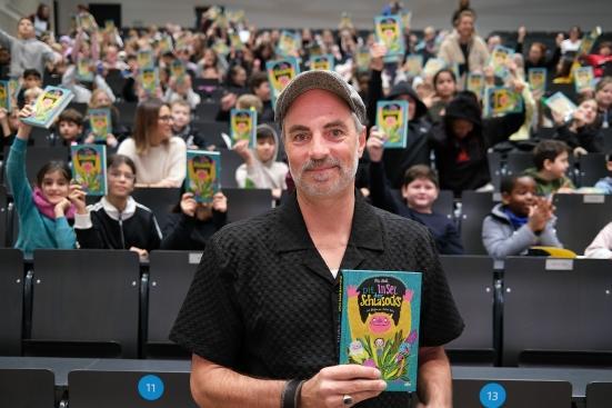 Autor Nils Mohl mit Kindern im Hörsaal.