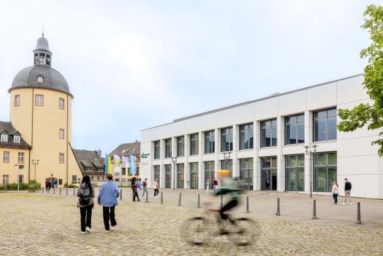 Studierende und ein Fahrradfahrer sind auf dem Schlossplatz am Unteren Schloss unterwegs.