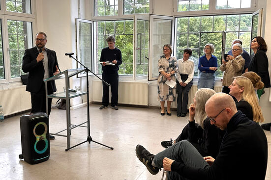 Dr. Petrico von Schweinichen, Vorstandsmitglied des Lions Club Siegen-Rubens, steht am Rednerpult. Vor ihm sitzen die Gäste des Rundgangs.
