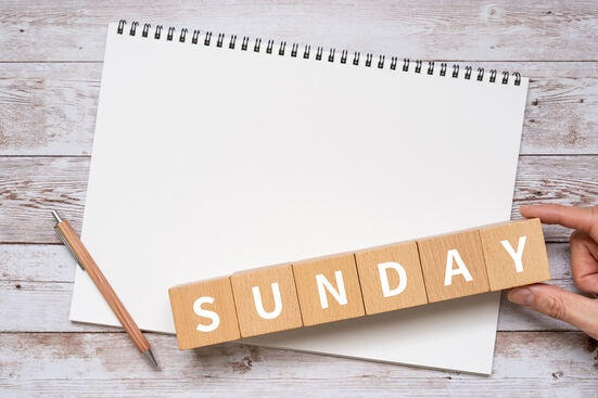 Foto mit einem leeren Kalenderblatt, einem Bleistift und dem Wort Sunday aus Holzklötzchenin Holz