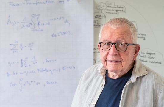 Dr. Bernd Dreseler vor einer Tafel mit mathematischen Formeln.