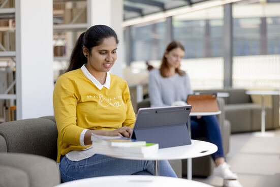Zwei Studentinnen, die in der UB an ihren Laptops arbeiten