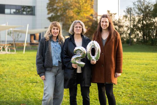 Drei Mitarbeiterinnen stehen auf der LEO-Wiese und halten die Zahl 20 als Party-Luftballons in den Händen.