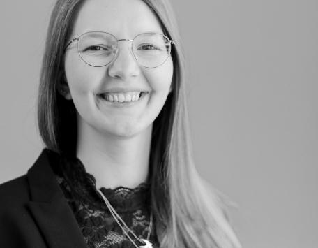 Eine Frau mit Brille und einem breiten Lächeln, die in die Kamera schaut.