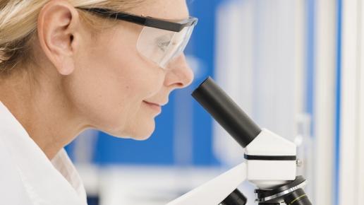 Frau mit Blick durch Mikroskop