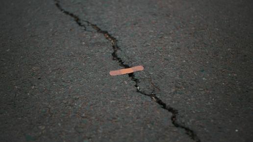 Riss im Asphalt, über das ein Pflaster geklebt ist