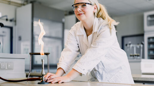 Studentin im Chemielabor führt Experimente mit einem Brenner durch
