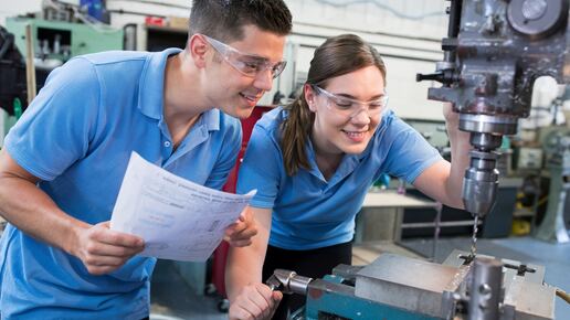 Engineer Instructing Female Apprentice On Use Of Drill
