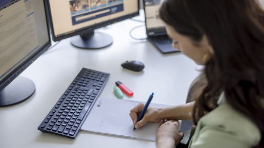 Mitarbeiterin macht sich Notizen am Arbeitsplatz