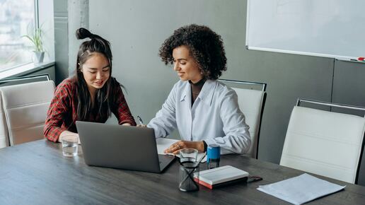 Zwei Frauen sitzen an einem Besprechungstisch.