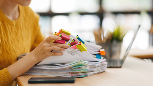 Junge Frau, die geheftete Aufsätze durchguckt.