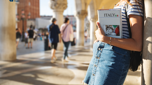Female tourist in Venice holding a book on Italy in her arm.