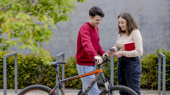 Zwei studierende stehen vor einem Fahrrad.